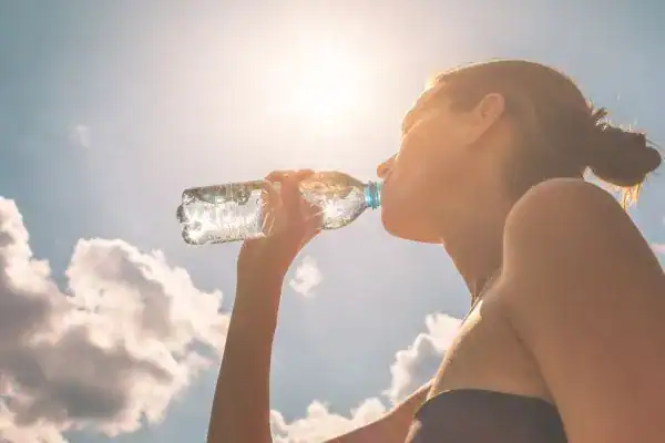Hydration: The Secret Ingredient for a Toned Stomach and Enhanced Fitness 3 Image of woman drinking water to hydrate Burgess Hill after run.