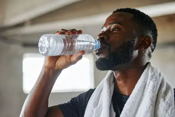 Hydration: The Secret Ingredient for a Toned Stomach and Enhanced Fitness 1 Image of man drinking water to improve hydration Burgess Hill after work out.